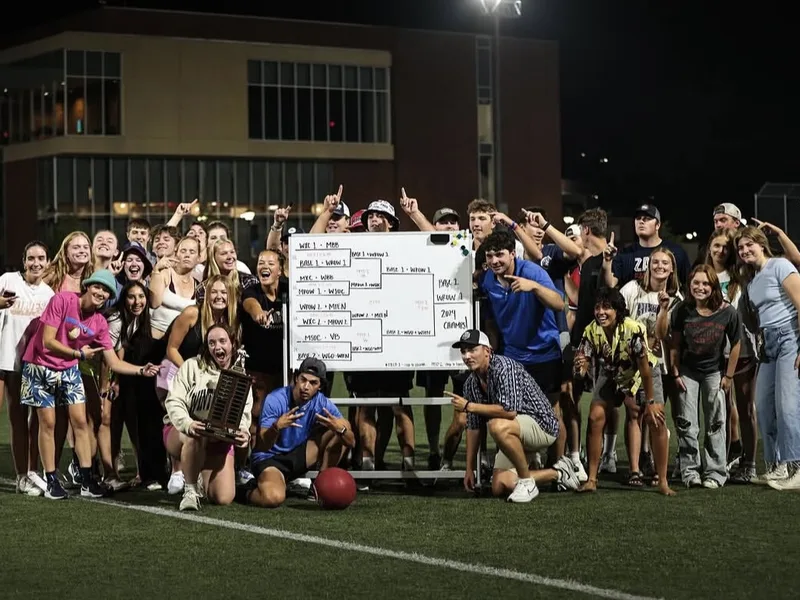 Gonzaga student-athletes celebrating around a tournament bracket with the trophy