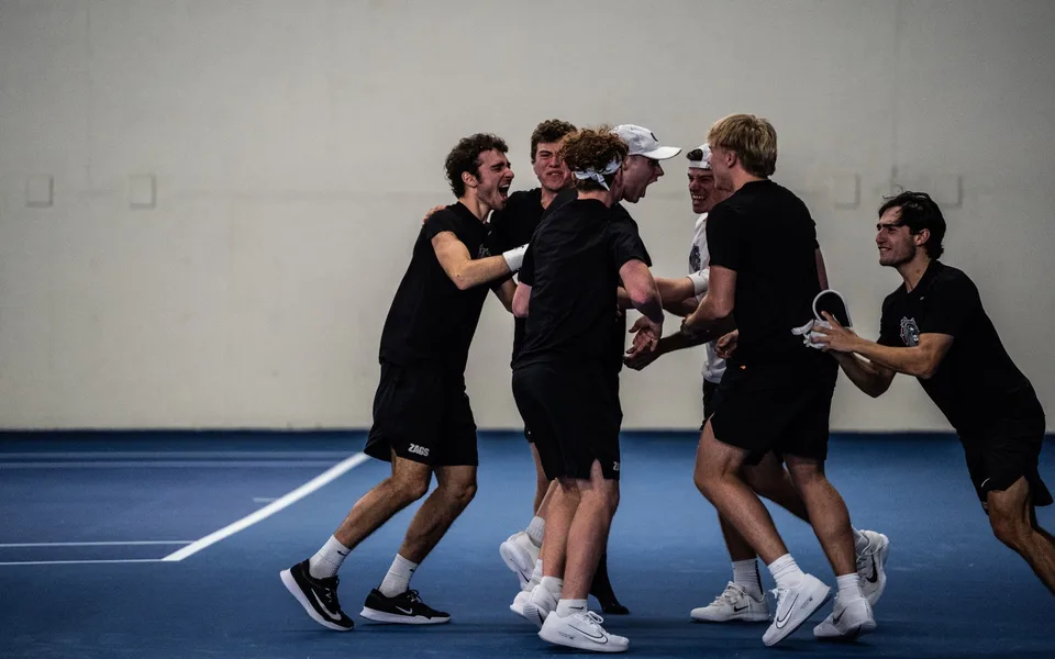 Oscar and the Gonzaga men's tennis team celebrating together on court
